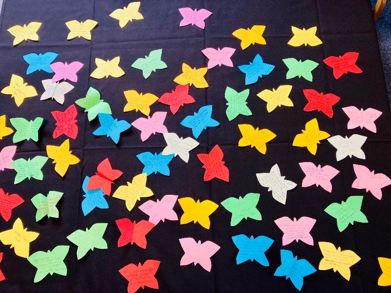 Dozens of multi-coloured paper butterflies on a black stage