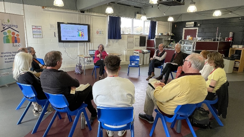 Delegates at a seminar at the SEBA Partners in Mission Tonbridge, sat on chairs in a circle, listening to Penny Marsh