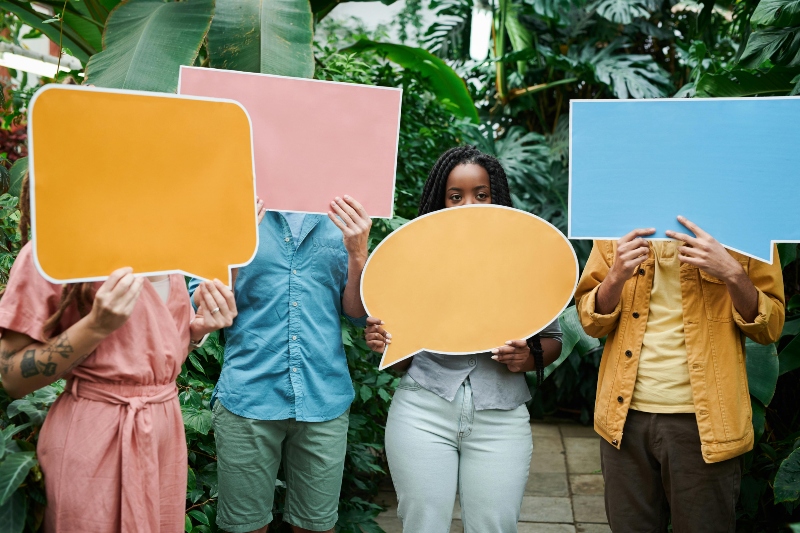 4 people hold speech bubble signs covering their faces
