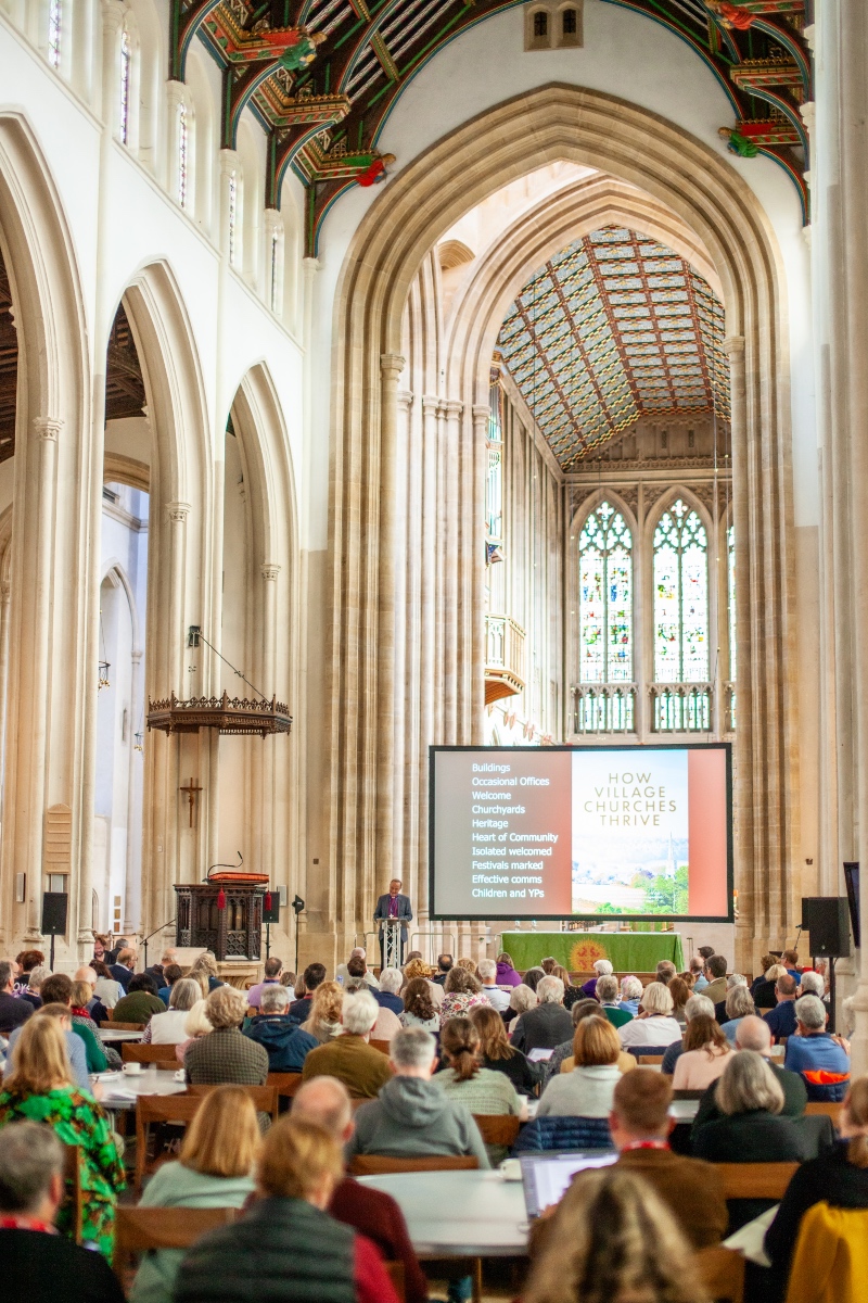 Photo from the back of a cathedral shows delegates listening to a speaker at the Love Rural conference