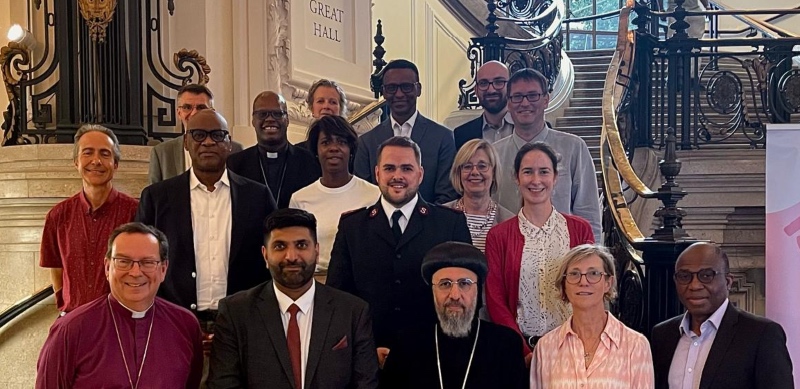 Churchworks representatives - 17 people, a mixture of men and women, stood in 3 rows on steps in Parliament, in front of a sign for The Great Hall