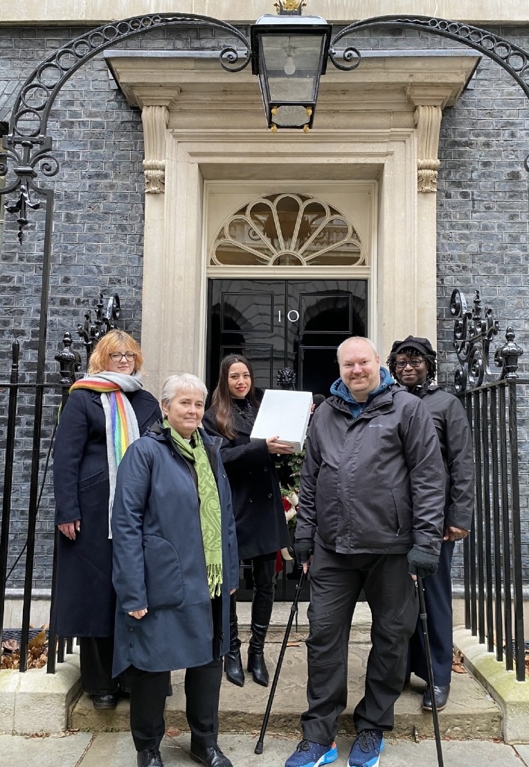 Let's End Poverty at 10 Downing Street - 5 people (4 women, 1 man) in front of the door of 10 Downing Street, holding a petition