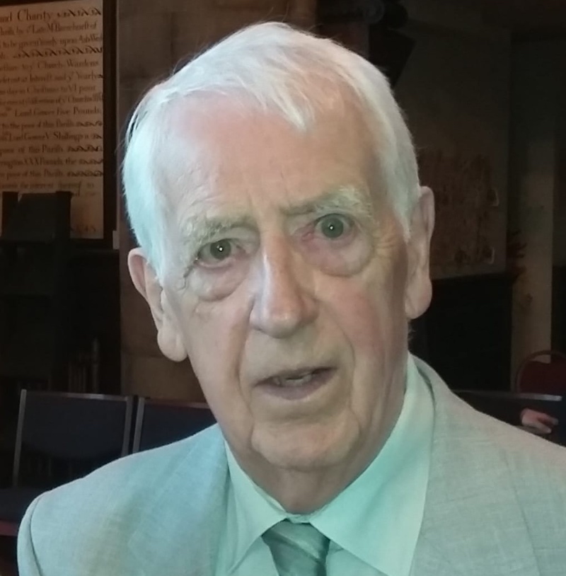 The Revd Roy Deller, wearing a grey suit and shirt and tie