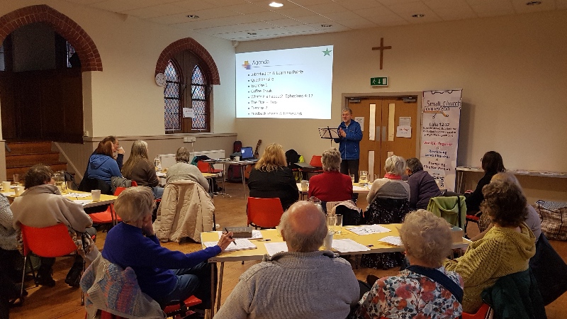 Around 17 people sit around tables in Union Church listening to teaching from Martin Taylor