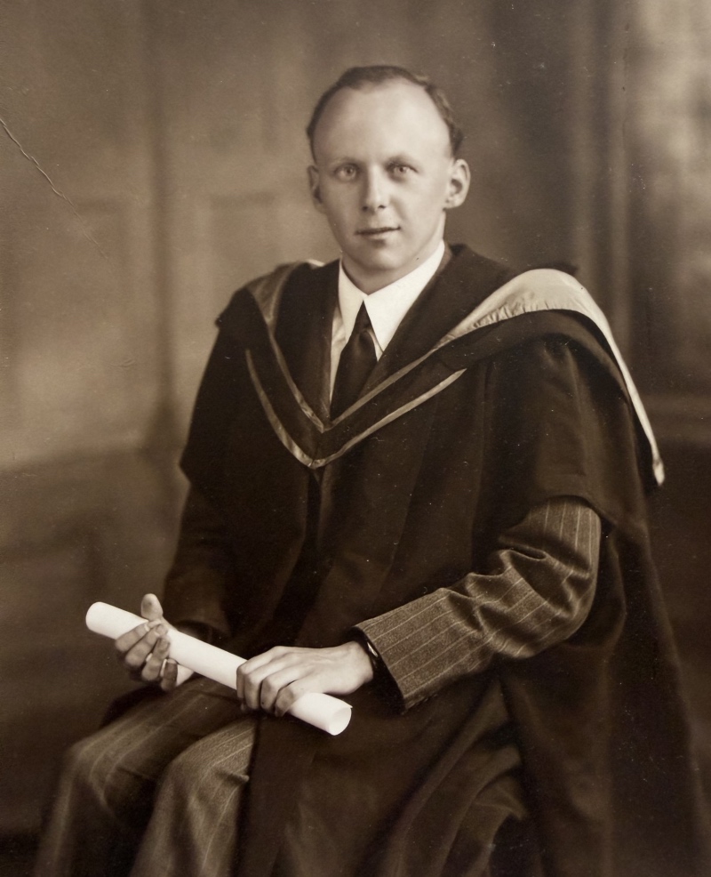 George Bonson as young man - a black and white photograph showing him wearing a gown and holding a scroll